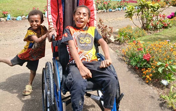 Agasave delights in his new wheelchair in Papua New Guinea.
